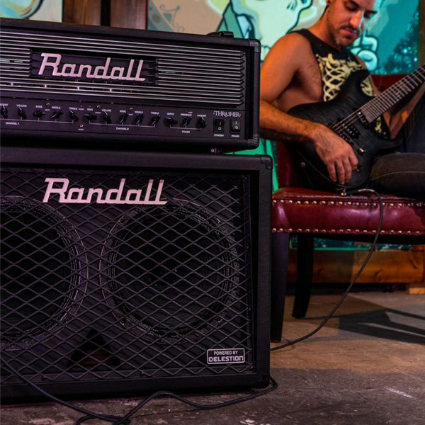 man sitting in leather chair playing electric guitar behind Randall amplifier
