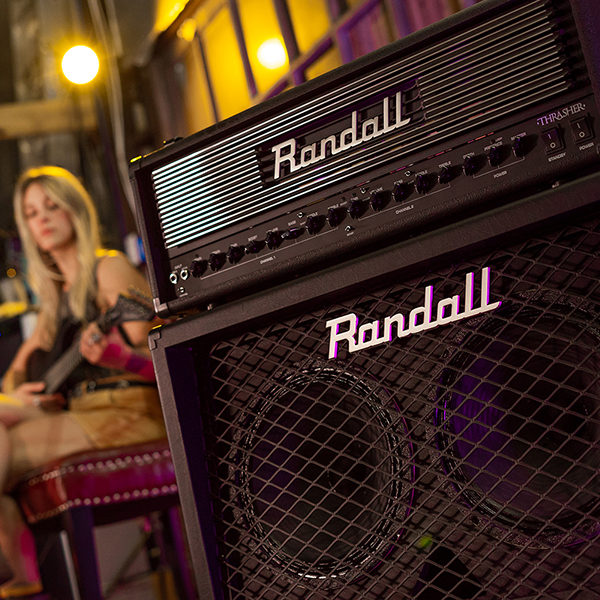 Randall amplifier and amplifier head with woman playing electric guitar in background