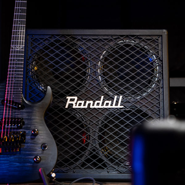 partial view of electric guitar in front of Randall cabinet